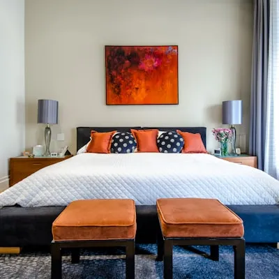 Dormitorio con cama tapizada y acentos en naranja